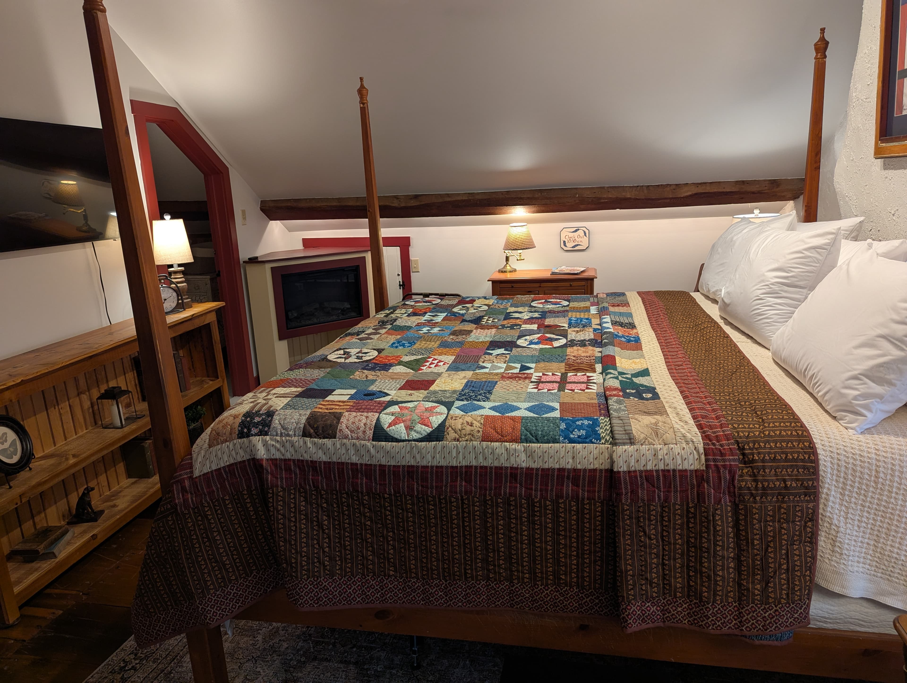 bedroom from side of bed showing TV, shelf and entrance to bath